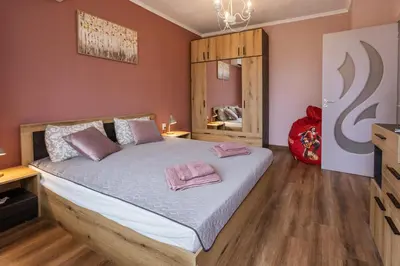 a bedroom with a bed with pink pillows on it at Happy Lazur in Burgas City