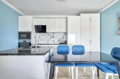 a kitchen with a dining table and blue chairs at Perfect Seaside Retreat in Sveti Vlas Relax Complex by Flat Mаnаger in Sunny Beach