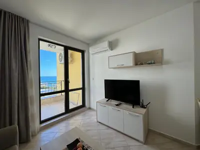 a living room with a television and a view of the ocean at HORIZON 13 'A' APARTMENT Sveti Vlas in Sveti Vlas