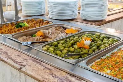 a buffet with several trays of food on a counter at Hotel Riva - All Inclusive in Sunny Beach
