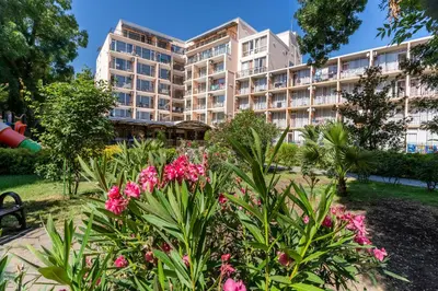 a large building with pink flowers in a park at Hotel Riva - All Inclusive in Sunny Beach