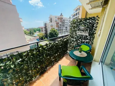 a balcony with green chairs and tables on a building at Blue Marine - Daneli Apartment in Sunny Beach