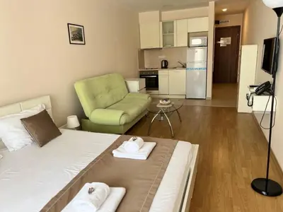 a small room with a bed and a green chair at Seaside Serenity Studio - Premier Fort Beach in Sveti Vlas
