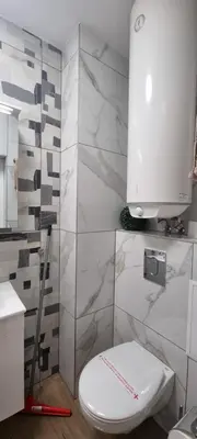 a white bathroom with a toilet and a sink at Central Luxe Apartament Mimoza in Varna City