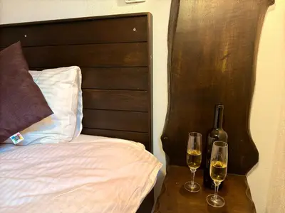 two glasses of wine on a table next to a bed at Arthotel Oscar II Sozopol in Sozopol