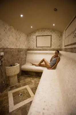a woman sitting on a bed in a bathroom at Vineyards Resort - Apartment Panorama in Kableshkovo