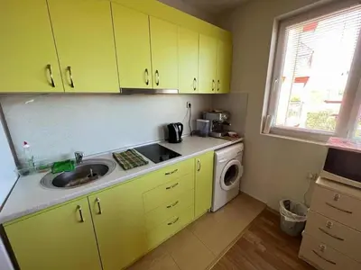 a kitchen with yellow cabinets and a sink and a washing machine at Oasis2 in Nesebar