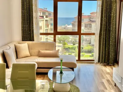 a living room with a couch and a large window at Sunshine apartment in Shkorpilovtsi