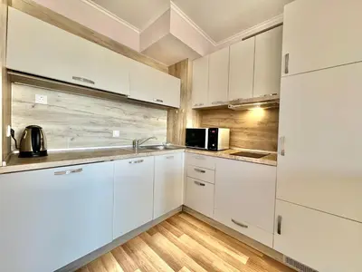 a white kitchen with white cabinets and a microwave at Sunshine apartment in Shkorpilovtsi