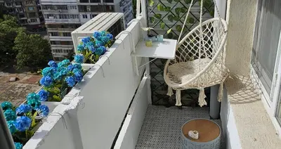 a white balcony with a chair and blue flowers at Апартамент ЛазуР in Burgas City