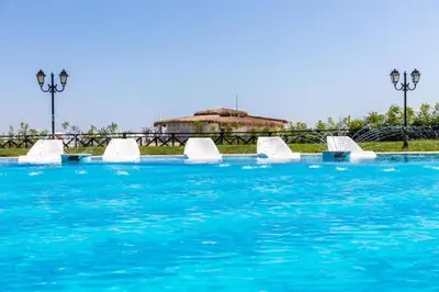 a pool of blue water with white chairs in it at Двуспални апартаменти Оазис Бийч клуб in Lozenets