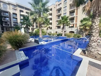 a swimming pool with palm trees in front of a building at Brandnew 3 Room Apartment with Poolview in Cascadas Resort in Sunny Beach