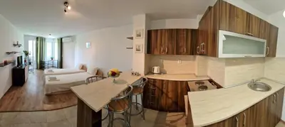 a kitchen with wooden cabinets and a living room at Дом Крумови in Burgas City