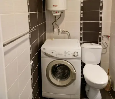 a small bathroom with a washing machine and a toilet at Дом Крумови in Burgas City