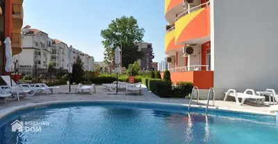 a swimming pool with tables and chairs next to a building at Студия в центре Солнечного берега in Sunny Beach