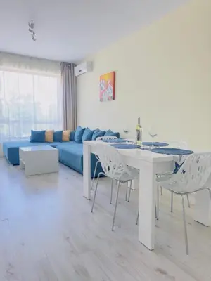 a living room with a table and a blue couch at Seaside View Apartment in Varna in Varna City