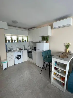 a kitchen with white cabinets and a table and chairs at Апартамент Лариди in Sozopol