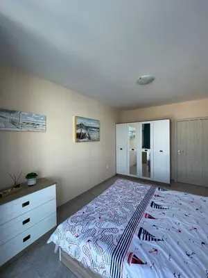 a bedroom with a large bed and a dresser at Апартамент Лариди in Sozopol