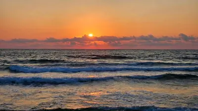 a sunset over the ocean with waves at Sea and Sand Apartment in Sozopol