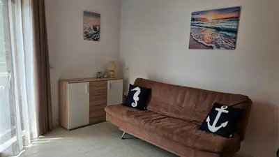 a living room with a brown couch and a table at Sea and Sand Apartment in Sozopol