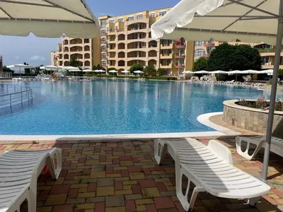 a large swimming pool with two white chairs and an umbrella at Midia SP Apartments in Aheloy