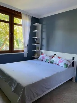 a bedroom with a large bed with a blue wall at Santa Marina, Lovely 1-bedroom apartment in Sozopol