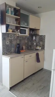 a kitchen with white cabinets and a microwave at Къща за гости Ани in Chernomorets