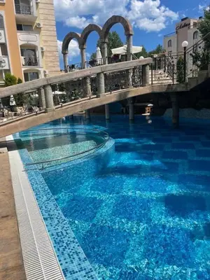 a bridge over a swimming pool with blue water at Sweety SP apartments in Sunny Beach