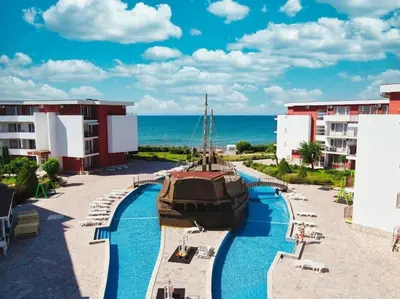 a view of a resort with a boat in the water at Привилидж первая линия in Sveti Vlas
