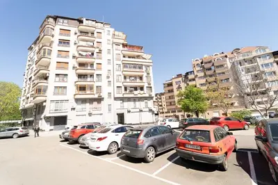 a parking lot with cars parked in front of tall buildings at Апартамент за гости Уют in Burgas City