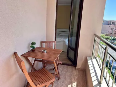 a balcony with a wooden table and two chairs at Апартаменти Bella Deluxe in Ravda