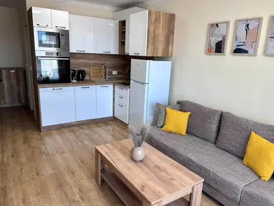 a living room with a couch and a table and a kitchen at Апартаменти Bella Deluxe in Ravda