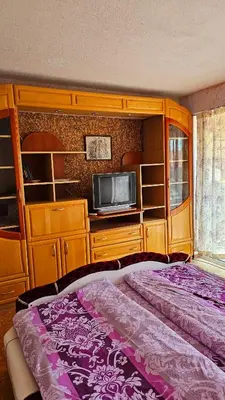 a bedroom with a bed and a tv and cabinets at Хоризонт in Nesebar