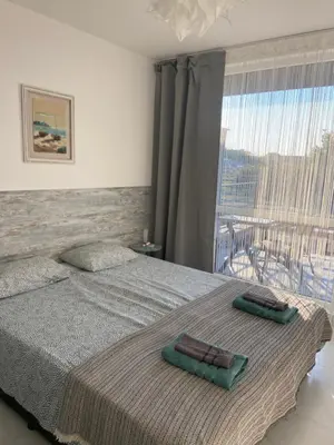 a bedroom with a bed and a large window at Порт Лозенец Морска Гледка - Port Lozenets Sea View in Lozenets