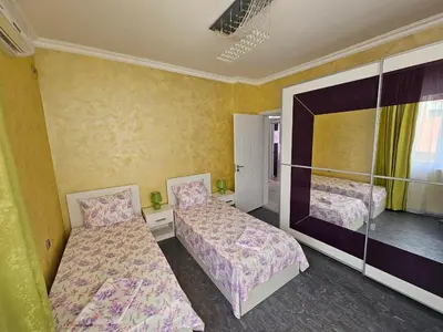 two beds in a room with yellow walls at Апартамент Елинор in Pomorie