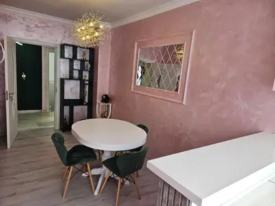 a dining room with a white table and green chairs at Апартамент Елинор in Pomorie