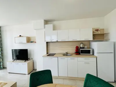 a small kitchen with white cabinets and a tv at HORIZON 6 'A' Apartment Sveti Vlas in Sveti Vlas