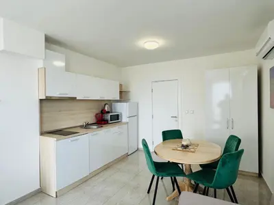 a kitchen with a table and green chairs in a room at HORIZON 6 'A' Apartment Sveti Vlas in Sveti Vlas