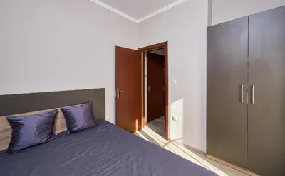 a bedroom with a purple bed and a closet at Bendita House in Pomorie