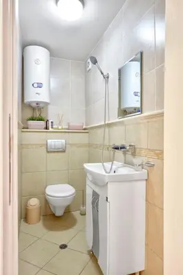 a white bathroom with a toilet and a sink at Sea Moreto Studio 1 in Burgas City