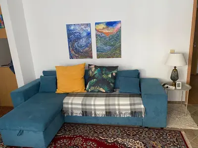 a blue couch in a living room with two paintings at Pomorie Chaika Home in Pomorie