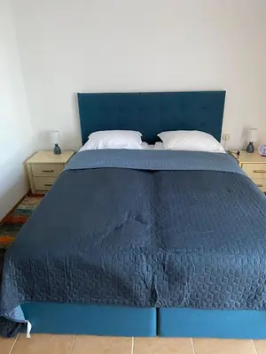 a bed with a blue comforter in a bedroom at Pomorie Chaika Home in Pomorie