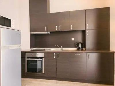 a kitchen with brown cabinets and a white refrigerator at Sorrento Sole Mare Apartments in Sveti Vlas