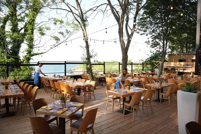 a restaurant with tables and chairs on a deck at PARADISE Bay Hotel in Sozopol