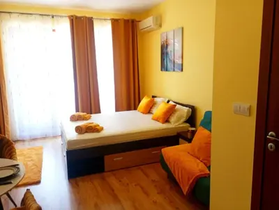 a bedroom with a bed with yellow walls and a window at One-room boutique at Sunrise All Suites in Obzor