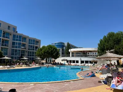 a large swimming pool with people sitting around it at Apartment with terrace in Spa Complex in Burgas City