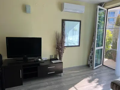 a living room with a flat screen tv and a mirror at Apartment with terrace in Spa Complex in Burgas City