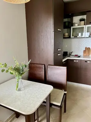 a kitchen with a table with a vase of flowers on it at Black Sea Breeze Apartment No 3 in Byala