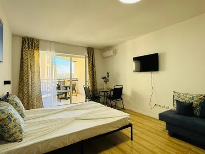 a bedroom with a bed and a tv and a balcony at ROYAL PALM 84 Studio Sveti Vlas in Sveti Vlas