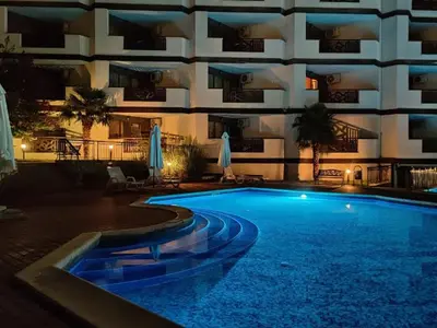 a swimming pool in front of a building at night at ROYAL PALM 84 Studio Sveti Vlas in Sveti Vlas